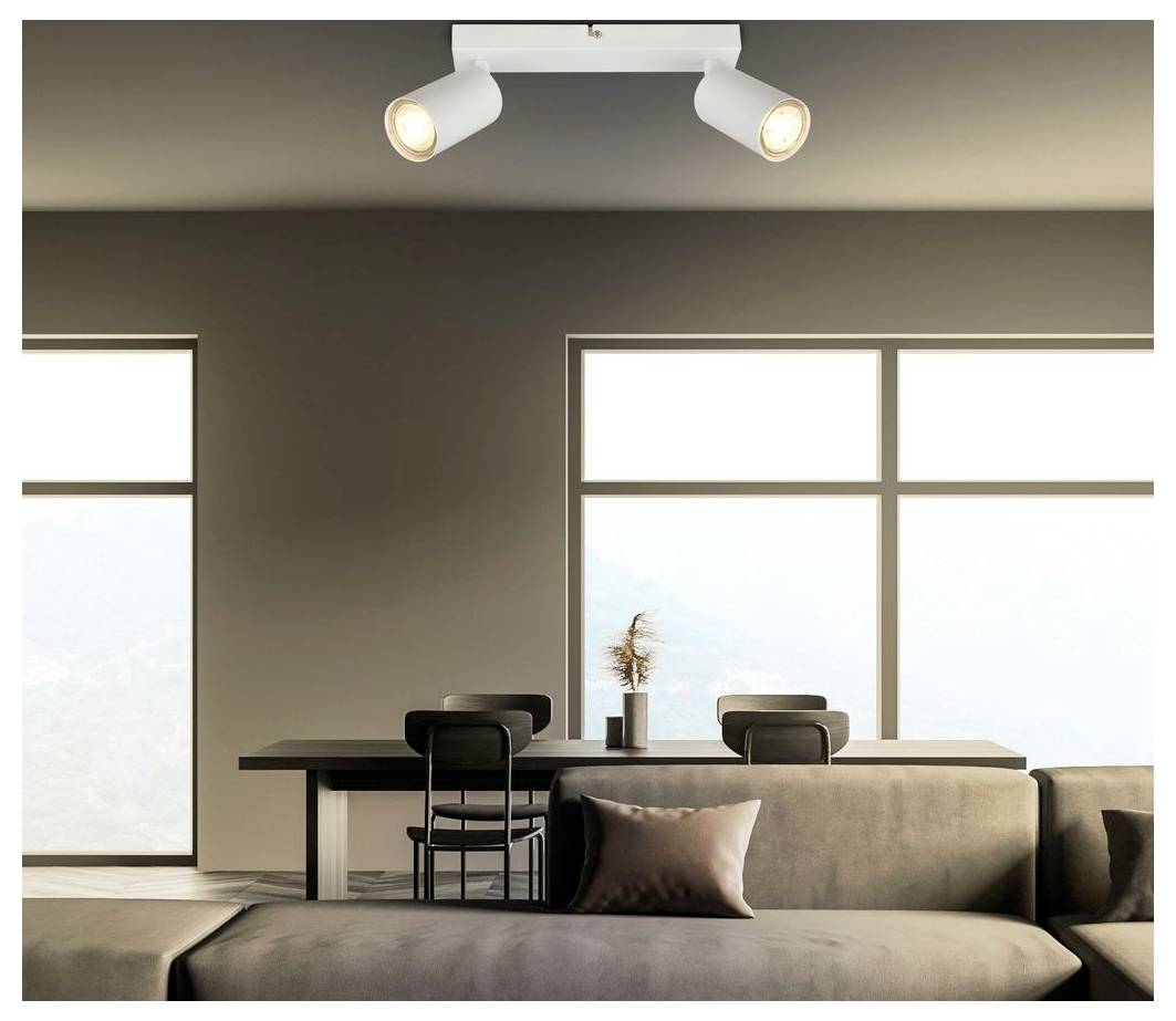 Modernes minimalistisches Wohnzimmer mit Sofa, Esstisch, Stühlen, großen Fenstern und Deckenspotlights in neutralen Tönen.