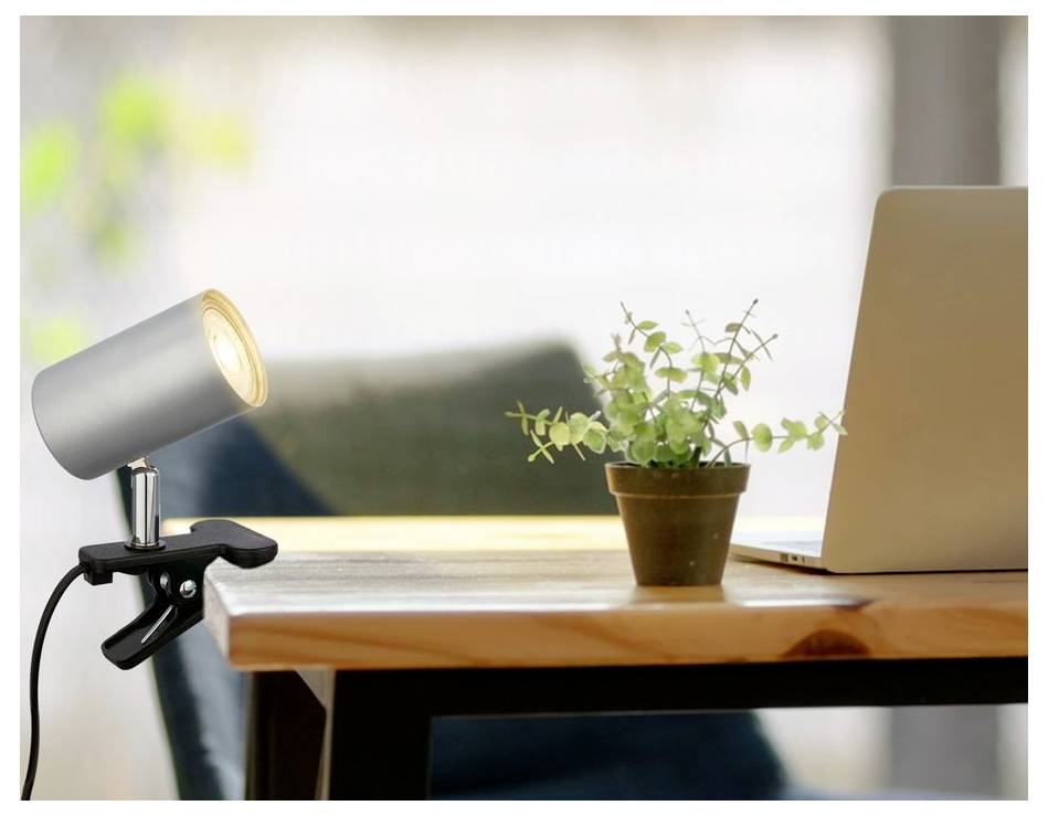 Schreibtischlampe mit Klemme an einem Tisch neben einer Topfpflanze und einem aufgeklappten Laptop in einer hellen Homeoffice-Umgebung.
