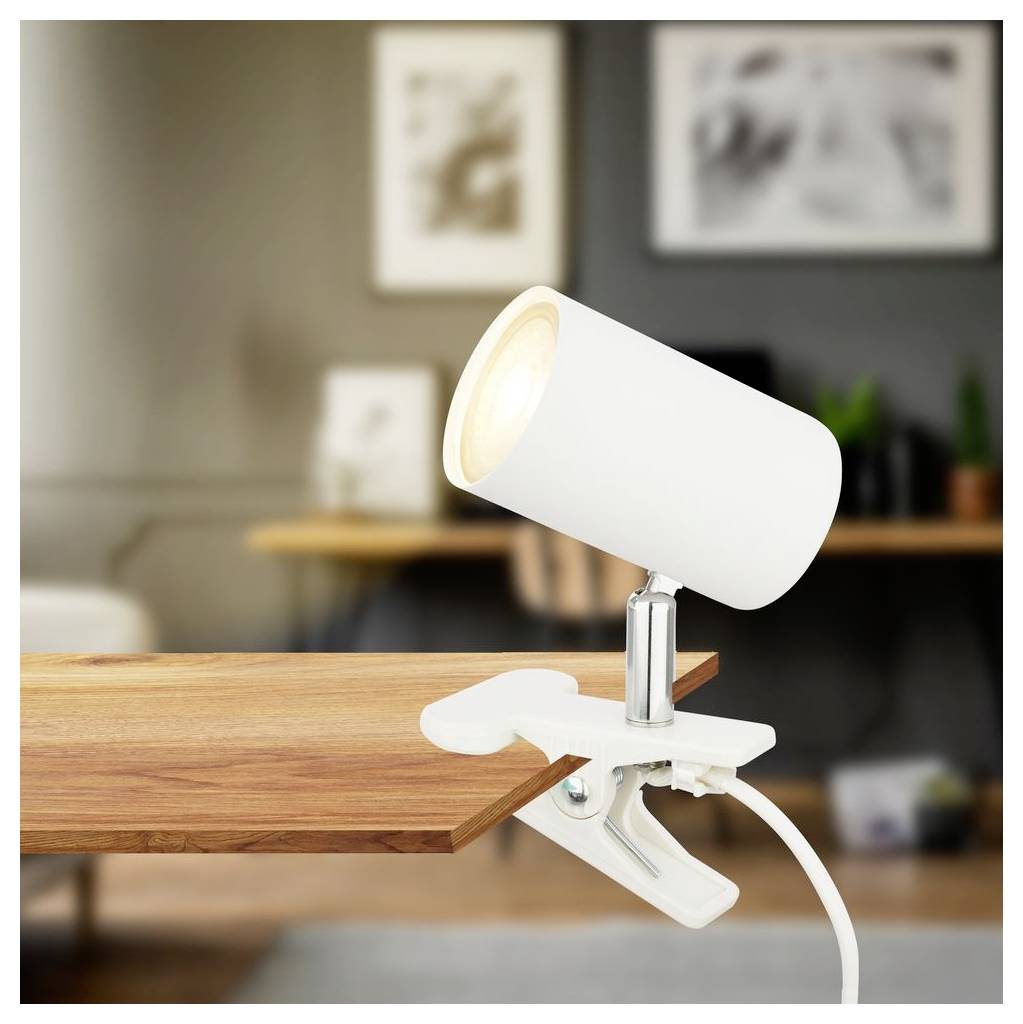 Weiße Klemmleuchte für den Schreibtisch an einer Holztischkante in einem modernen Raum angebracht, mit sichtbarem Stromkabel.