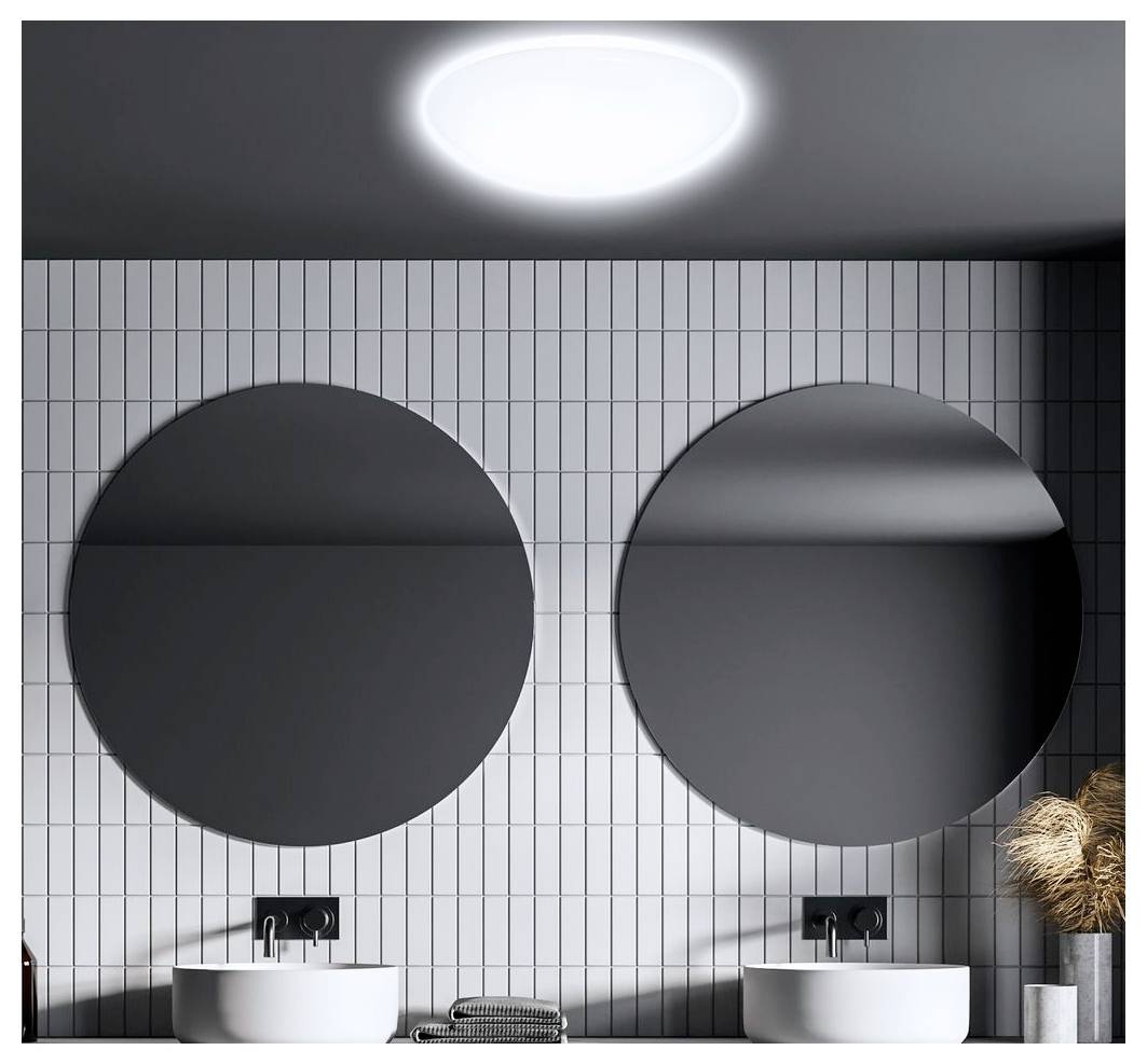 Modernes Badezimmer mit zwei kreisförmigen Spiegeln über Doppelwaschbecken an einer gefliesten Wand und einer hellen Deckenleuchte.