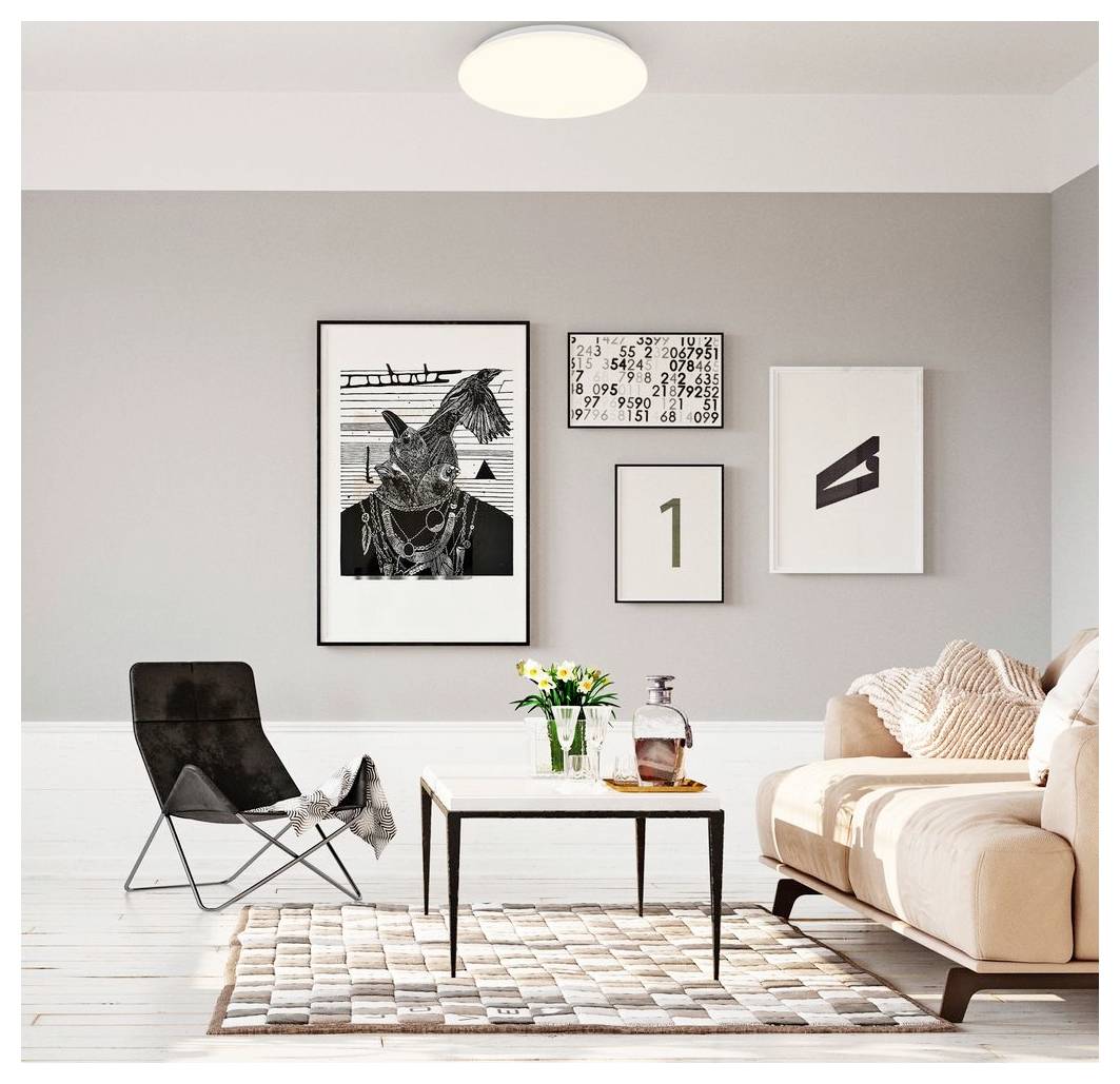 Modernes Wohnzimmer mit einem beigen Sofa, schwarzem Sessel, Couchtisch, Teppich und gerahmten Wandbildern an einer grauen Wand