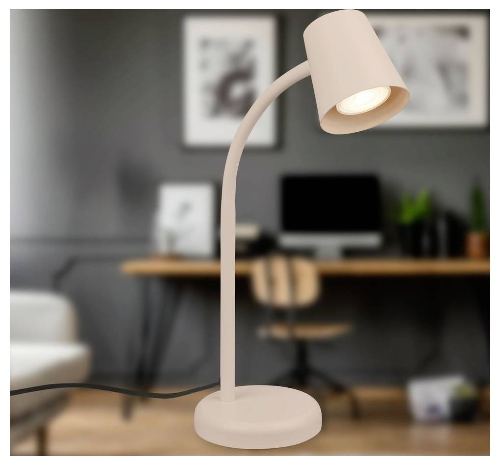 Rosa geschwungene Schreibtischlampe, die in einem unscharfen Homeoffice mit Schreibtisch, Stuhl und Wandkunst im Hintergrund leuchtet.