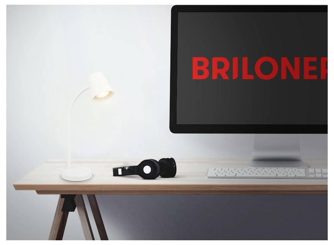 Schreibtisch mit Lampe und Kopfhörern neben einem Computermonitor, der das rote Wort 