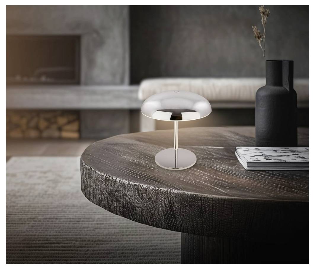Eine kleine moderne pilzförmige Tischlampe leuchtet auf einem runden Holz-Couchtisch neben einer schwarzen Vase und einer Zeitschrift in einem minimalistischen Wohnzimmer.