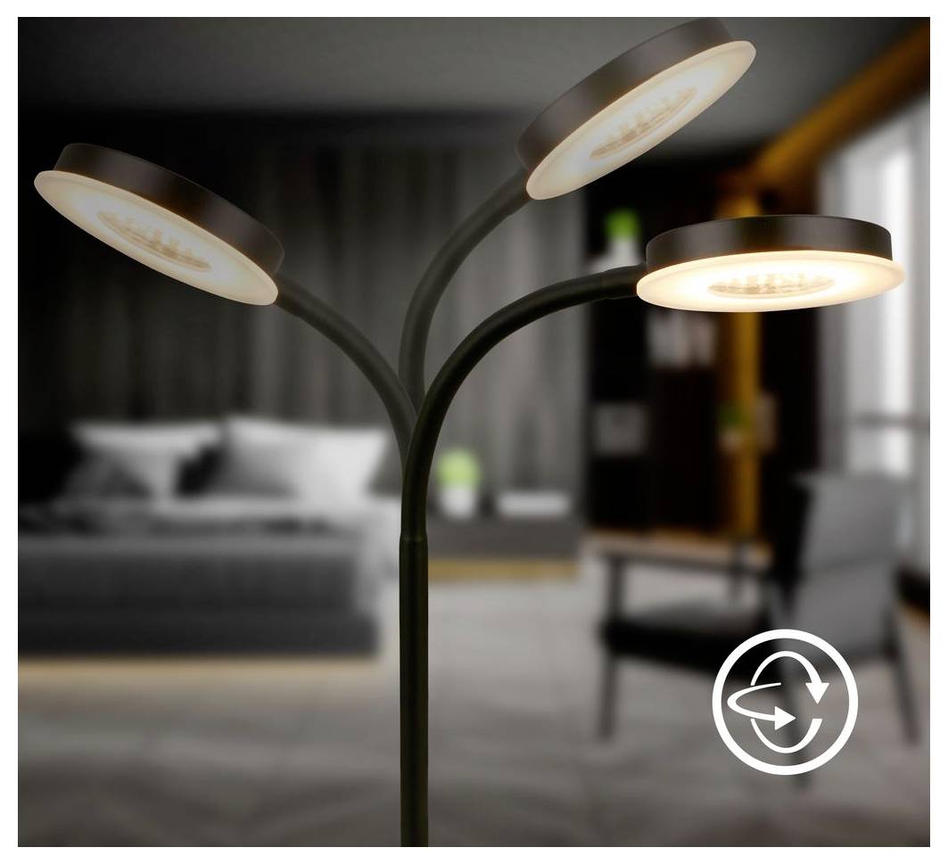 Dreiköpfige moderne Stehleuchte, die warm in einer unscharfen Schlafzimmerumgebung leuchtet, mit einem weißen Kreispfeil-Symbol unten rechts.