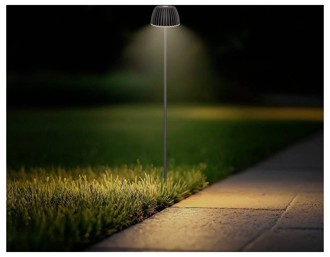 Ein kleines Solarwegelicht beleuchtet nachts das Gras neben einem Gehweg und wirft ein warmes Licht auf das Pflaster.