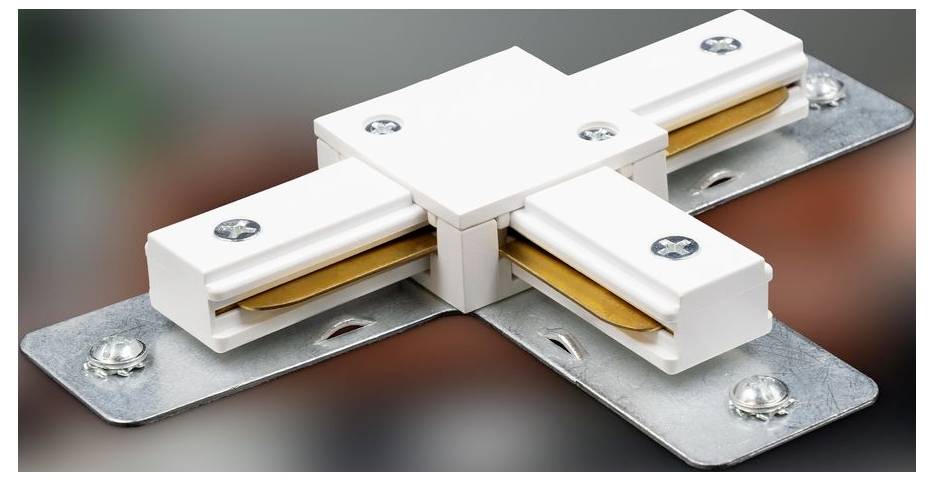 Weißer kunststoffgestützter elektrischer Steckverbinder, der vier Metallmontageplatte in Kreuzform verbindet, mit sichtbaren Schrauben und vergoldeten Kontakten.