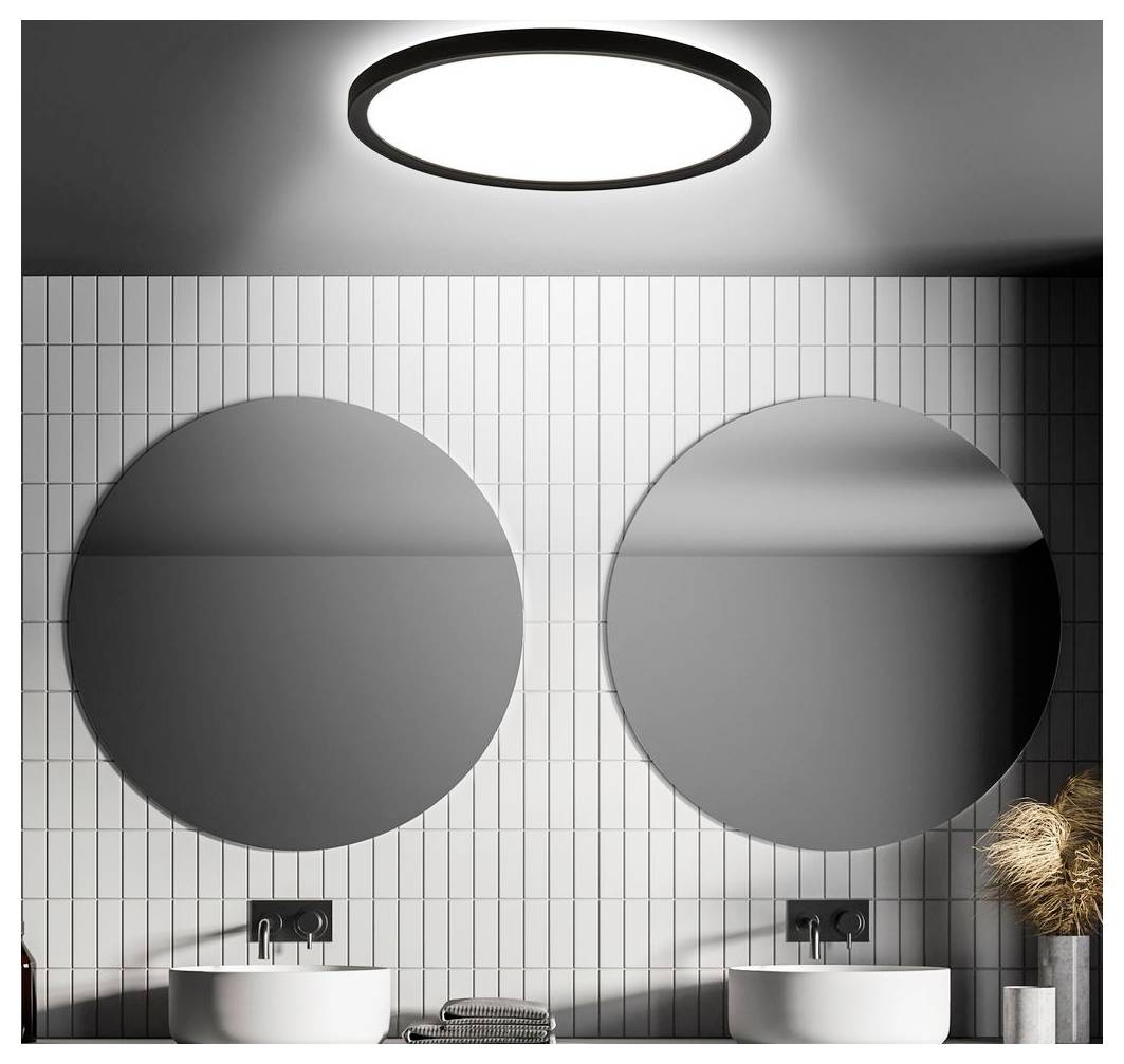 Modernes Badezimmer mit zwei runden Spiegeln über doppelten Aufsatzwaschbecken, gekachelte Wand und eine Deckenleuchte.