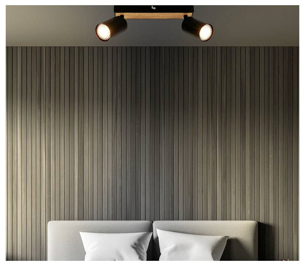 Modernes Schlafzimmer mit vertikal lamellierter Wand, Deckenspot und der Oberseite eines Bettes mit Kissen darunter.