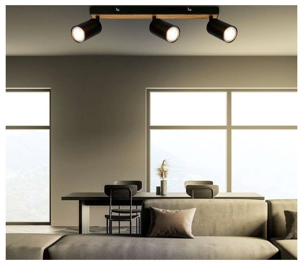 Modernes Wohnzimmer mit Sofa, Esstisch und Stühlen, großen Fenstern und drei Deckenstrahlern, die den Raum beleuchten.