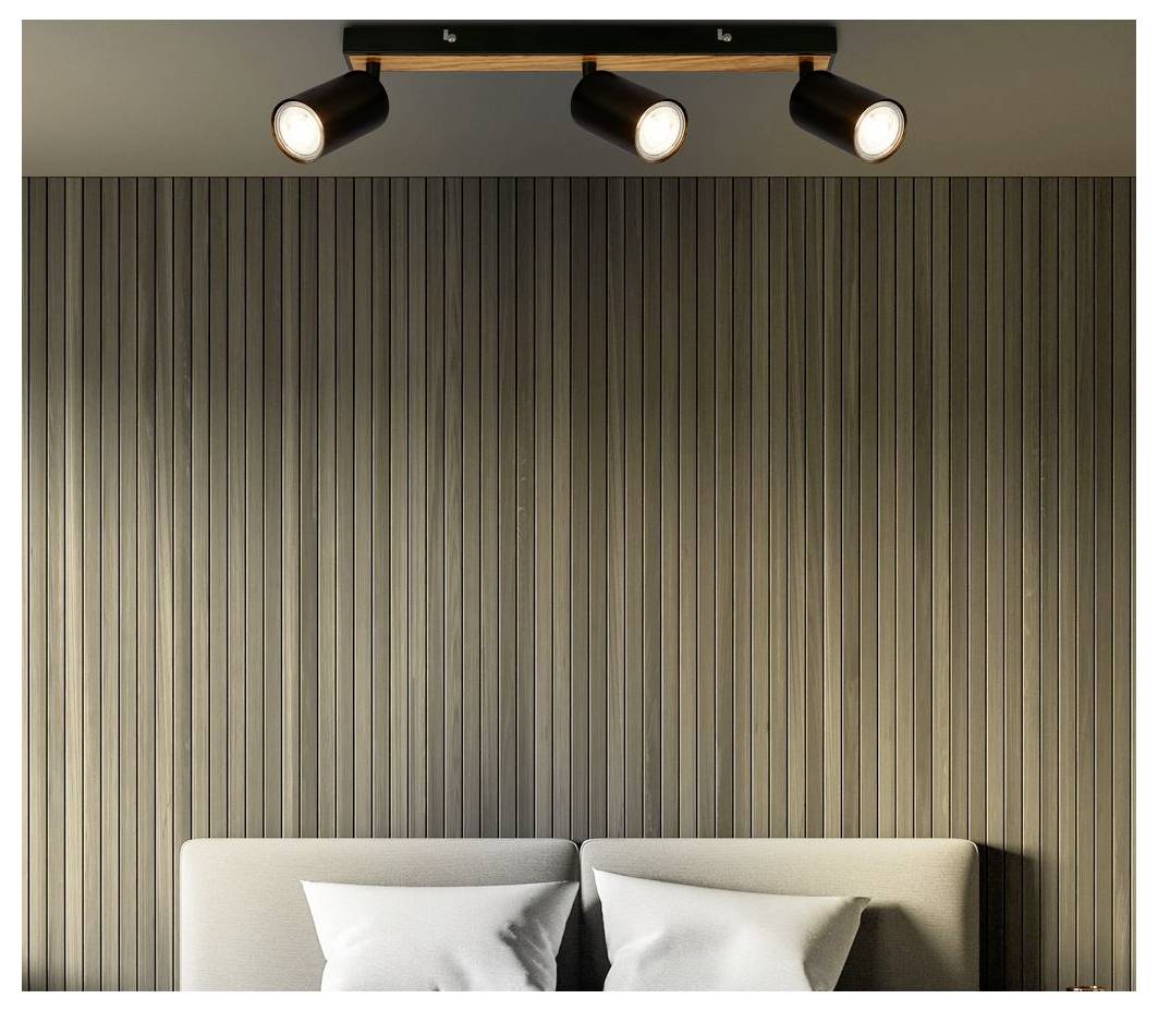 Drei leuchtende Deckenspotlights über einem Bett mit weißen Kissen vor einer vertikalen Holzlattenakzentwand.