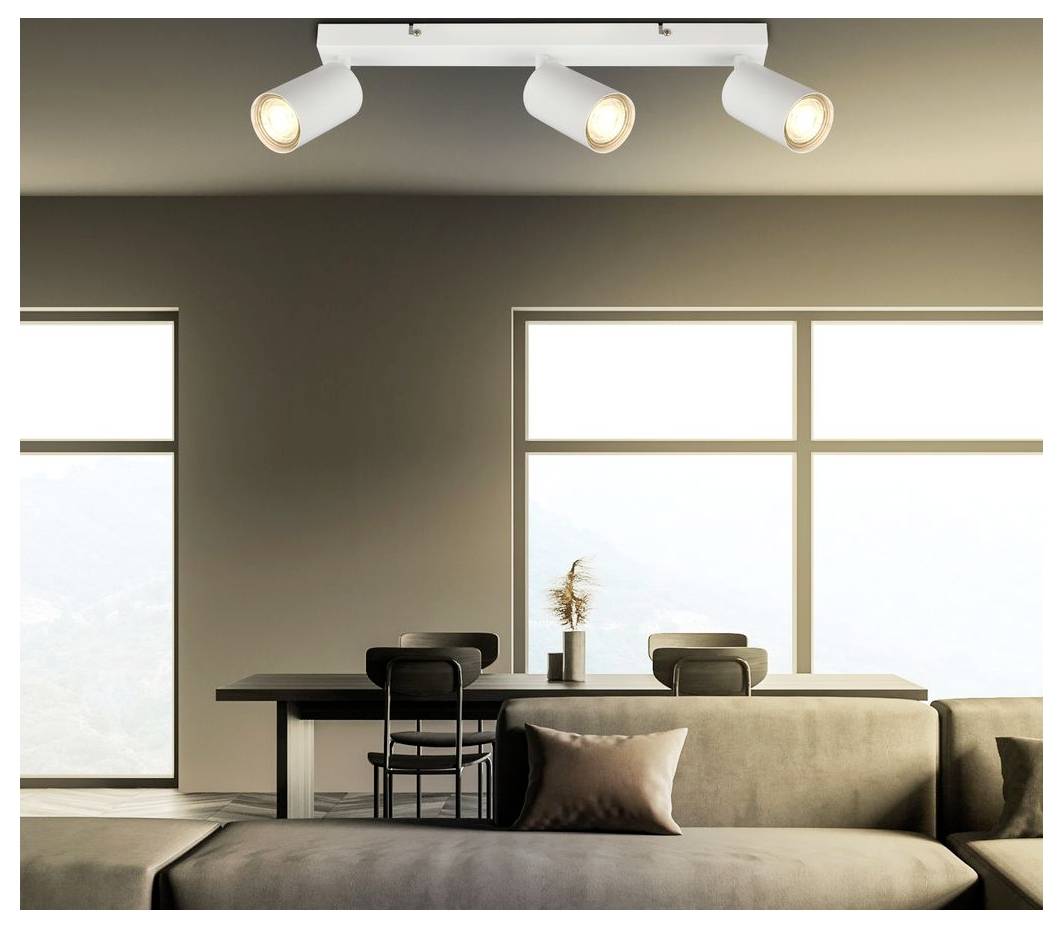Modernes, minimalistisches Wohnzimmer mit beigem Sofa, Esstisch und drei Deckenstrahlern neben großen hellen Fenstern.