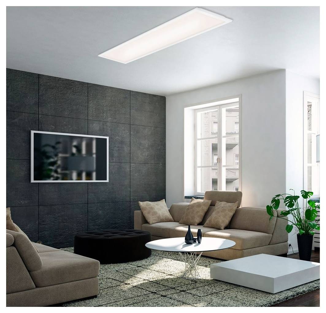 Modernes Wohnzimmer mit beigen Sofas, rundem weißem Couchtisch, schwarzem Pouf, an der Wand montiertem Fernseher und einer Topfpflanze neben einem hellen Fenster.