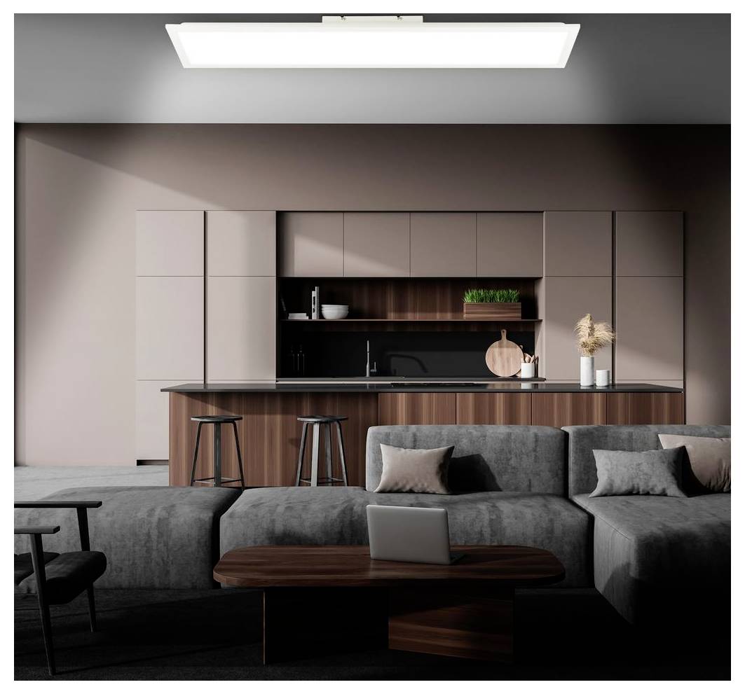 Modernes Wohnzimmer im offenen Grundriss mit grauem Ecksofa, Laptop auf dem Couchtisch und eleganter Küche mit Insel und Barhockern im Hintergrund.