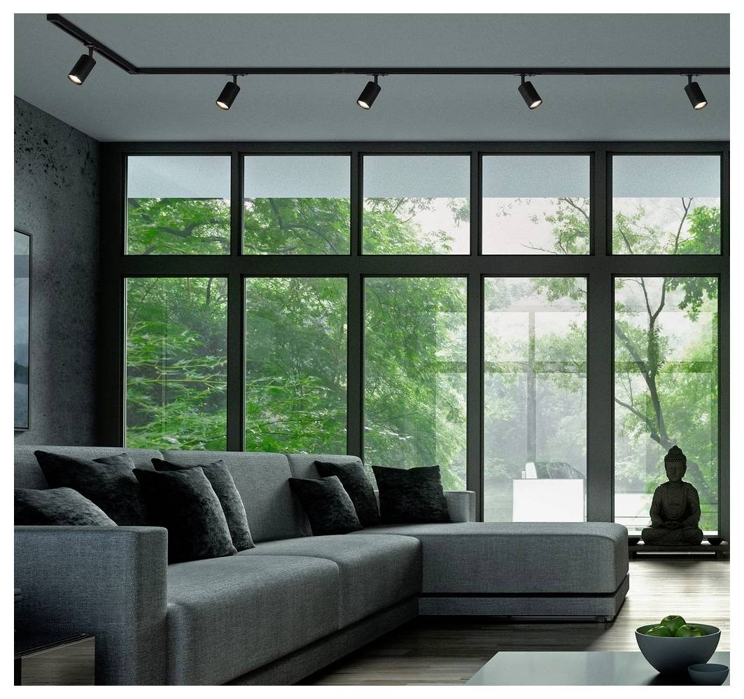 Modernes Wohnzimmer mit großem grauem Ecksofa, raumhohen Fenstern, Zimmerpflanzen und einer Buddha-Statue am Fenster.