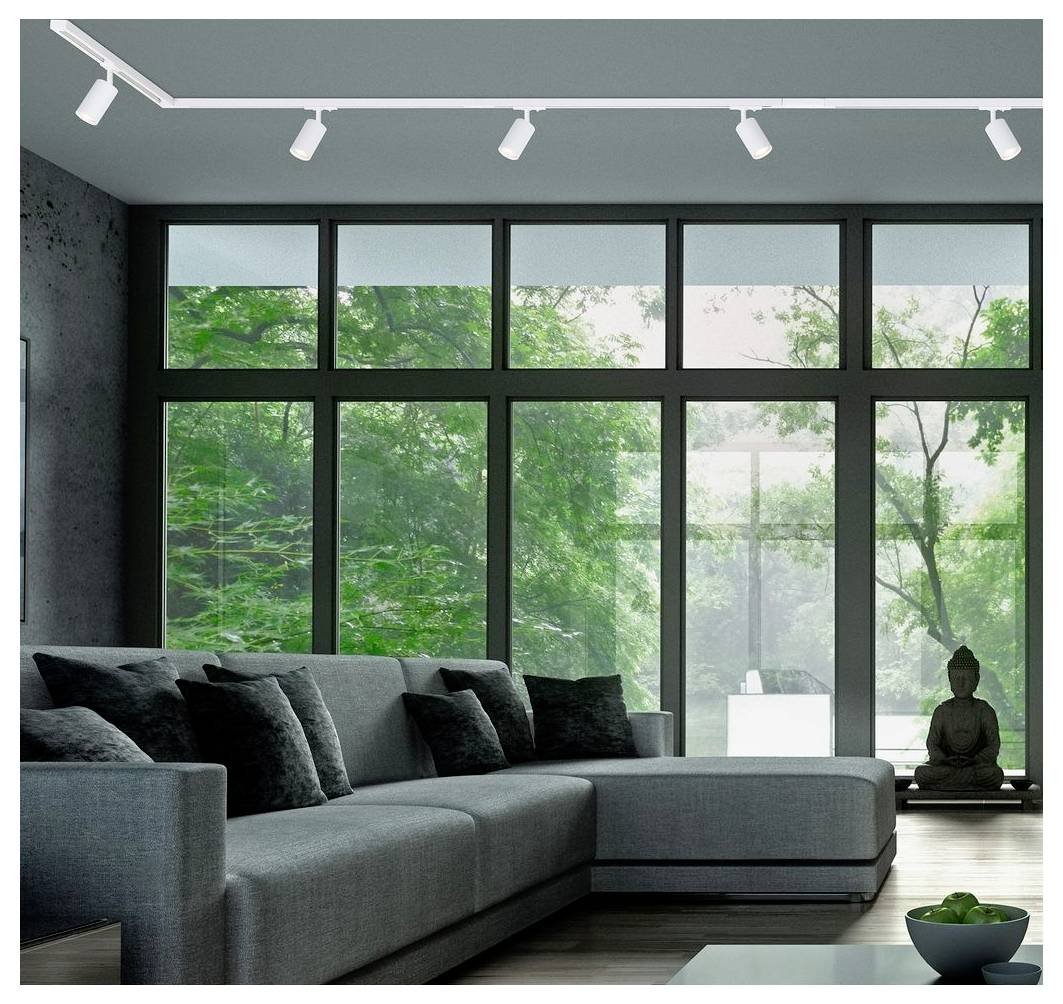 Modernes Wohnzimmer mit einem großen grauen Ecksofa, raumhohen Fenstern und einer kleinen Buddha-Statue neben der Glastür mit Blick auf Grünanlagen.