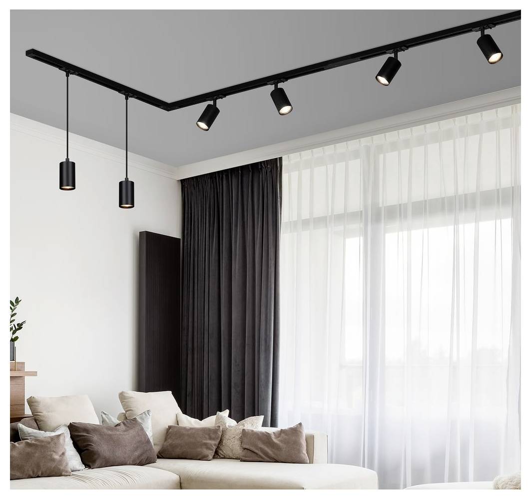 Modernes Wohnzimmer mit beigem Ecksofa, transparenten weißen Vorhängen und schwarzen Gardinen, beleuchtet von schwarzen Schienen- und Pendelleuchten an der Decke.