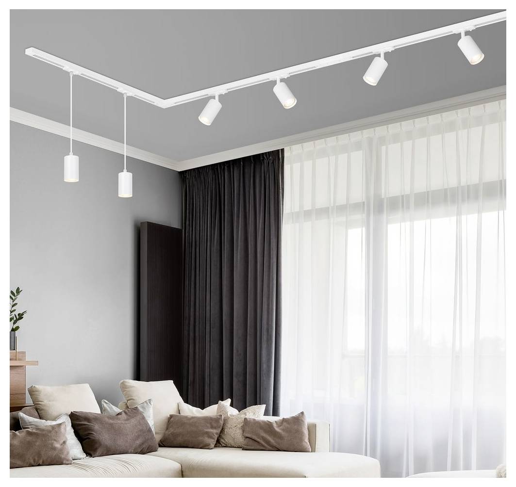 Modernes Wohnzimmer mit beigem Ecksofa und Kissen neben großen Fenstern mit transparenten Vorhängen, beleuchtet durch weiße Deckenleuchten mit Schienensystem.