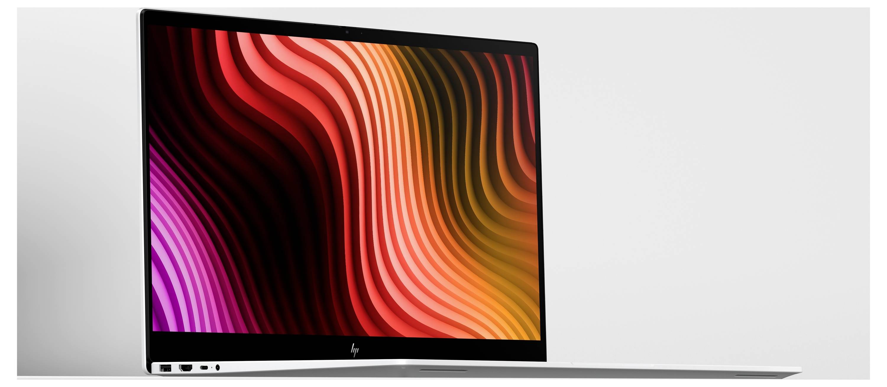 Ein dünner HP-Laptop mit geöffnetem Bildschirm, auf dem ein lebhafter, abstrakter Wellen-Hintergrundbild in Rot, Orange und Rosa angezeigt wird.