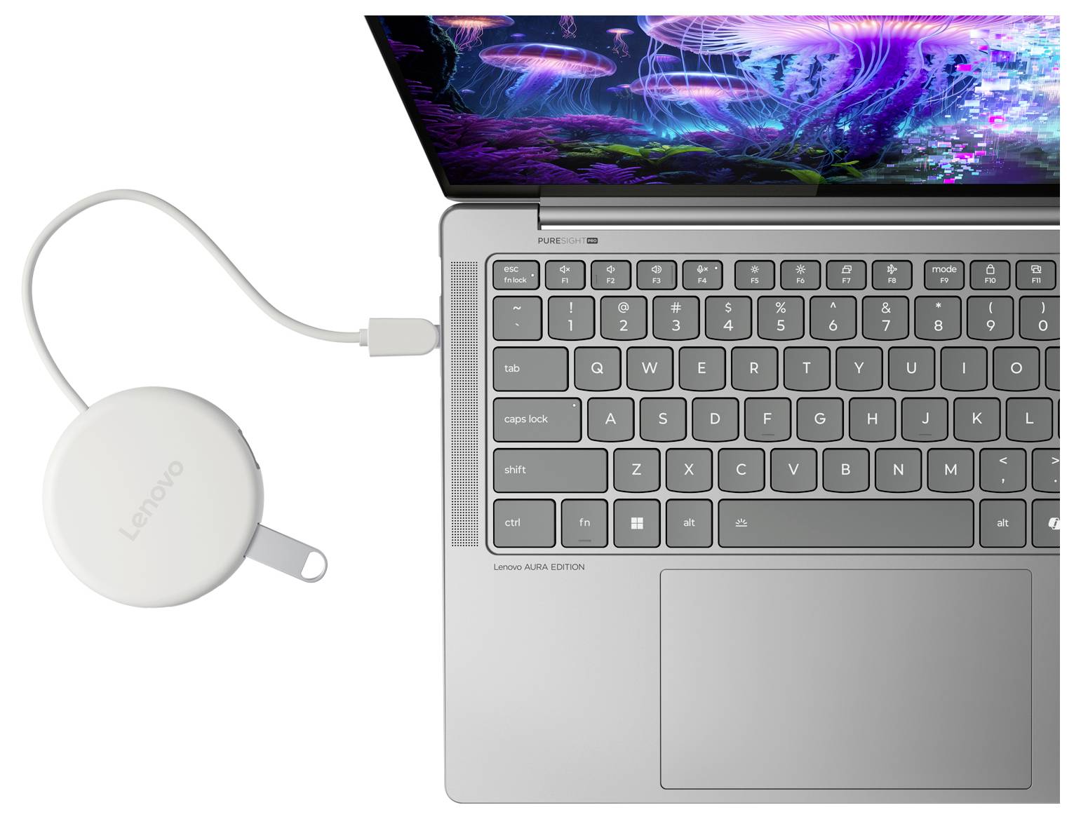 Ein weißer Lenovo-Laptop mit einem USB-C-Kabel, das mit einem kleinen runden Adapter oder Dock verbunden ist, das daneben liegt.