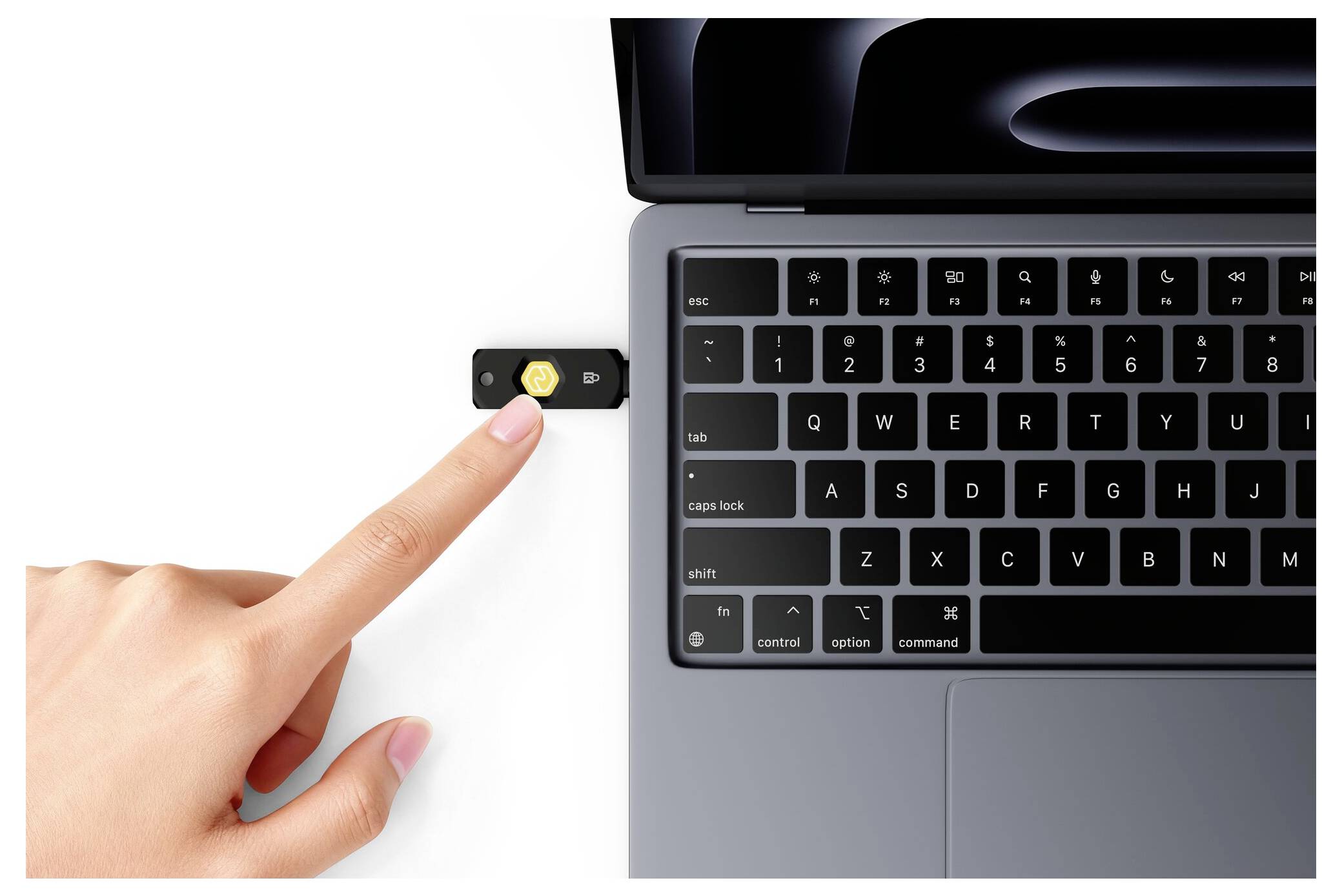 Eine Hand drückt einen USB-Stick in einen Laptop-Anschluss neben der Tastatur.