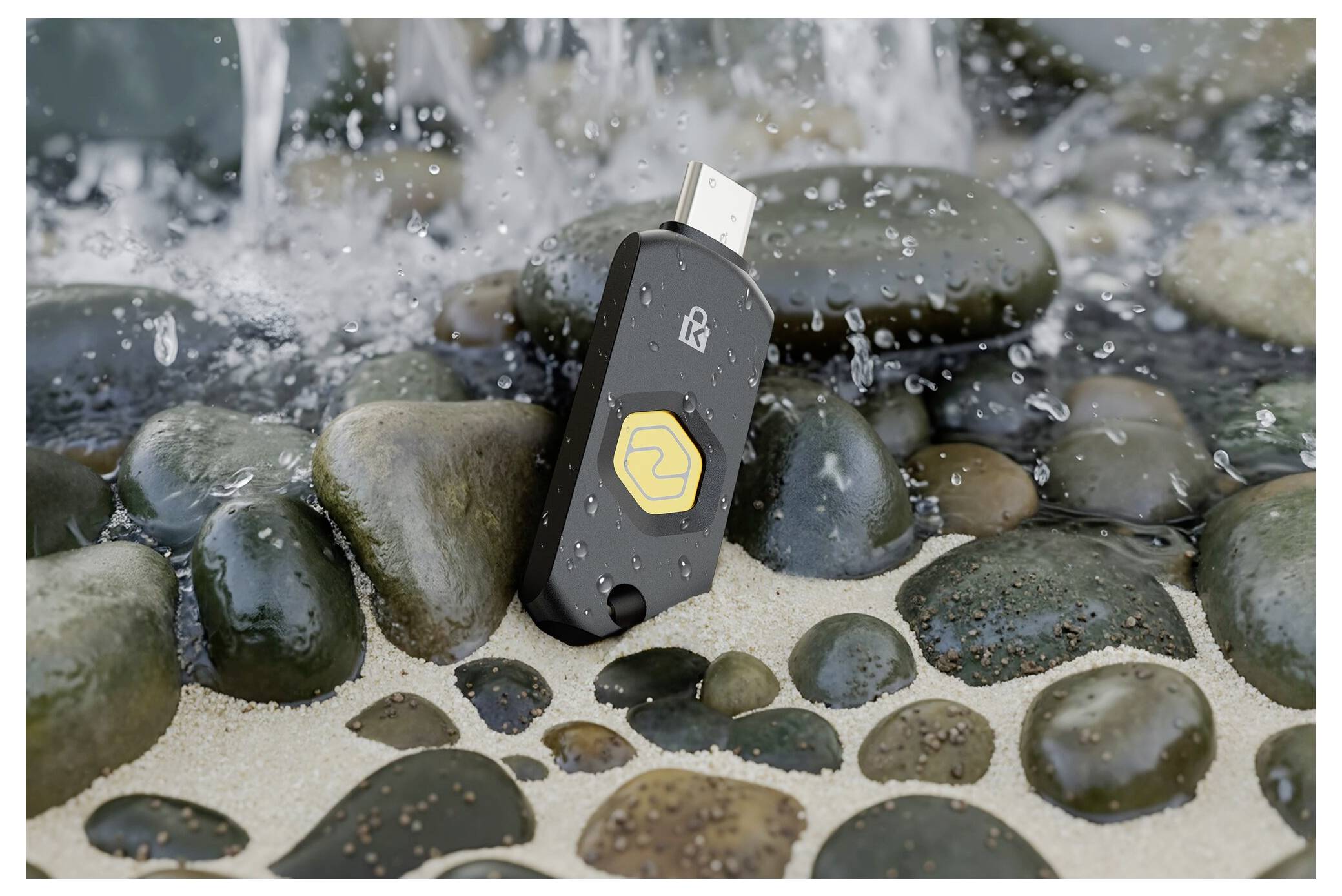 Ein wasserdichtes USB-Speicherlaufwerk mit gelbem Logo steht zwischen nassen Steinen, während Wasser um es herum spritzt.