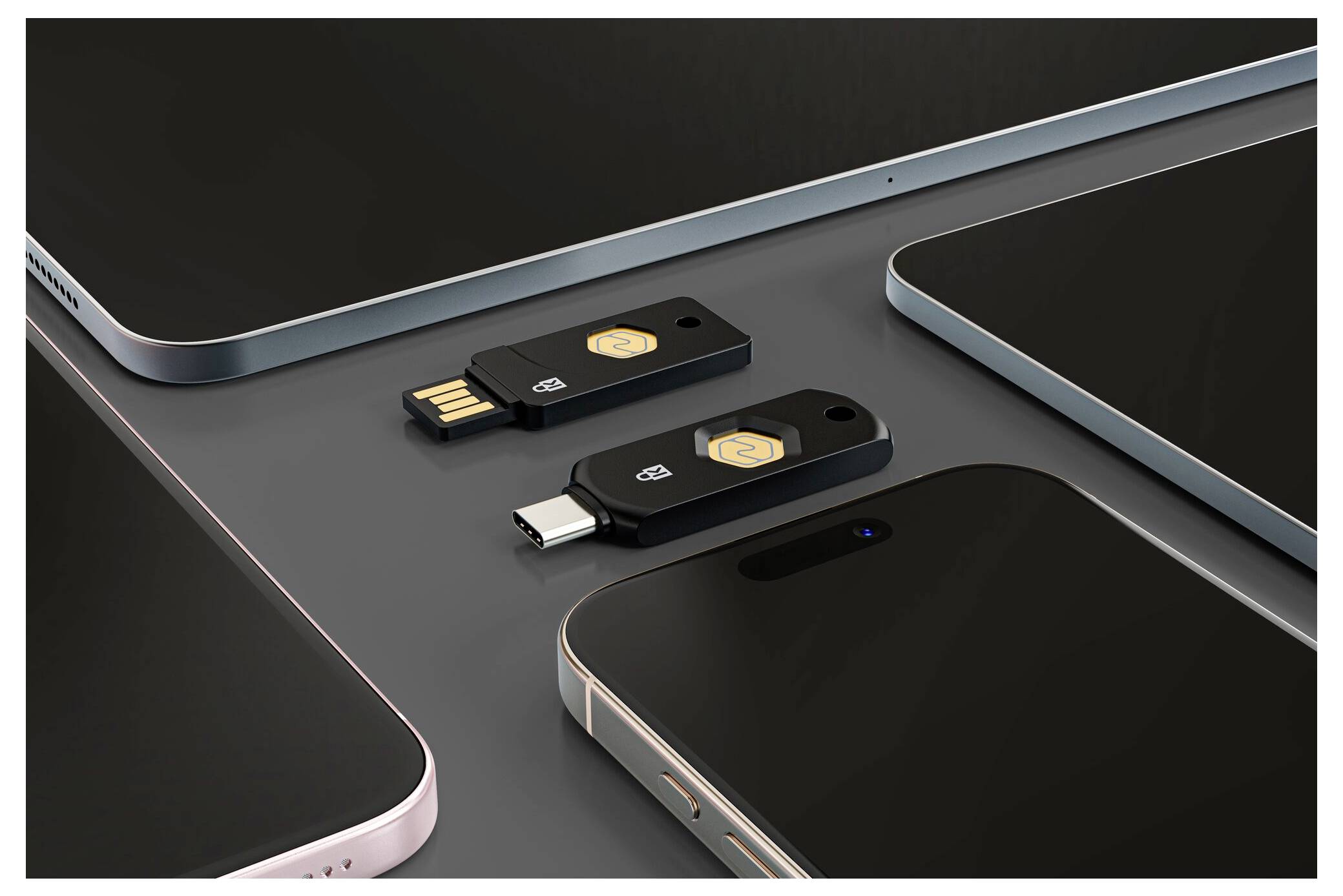 Zwei USB-Speichersticks, einer mit USB-A und einer mit USB-C, angeordnet zwischen mehreren Smartphones oder Tablets auf einer dunklen Oberfläche.
