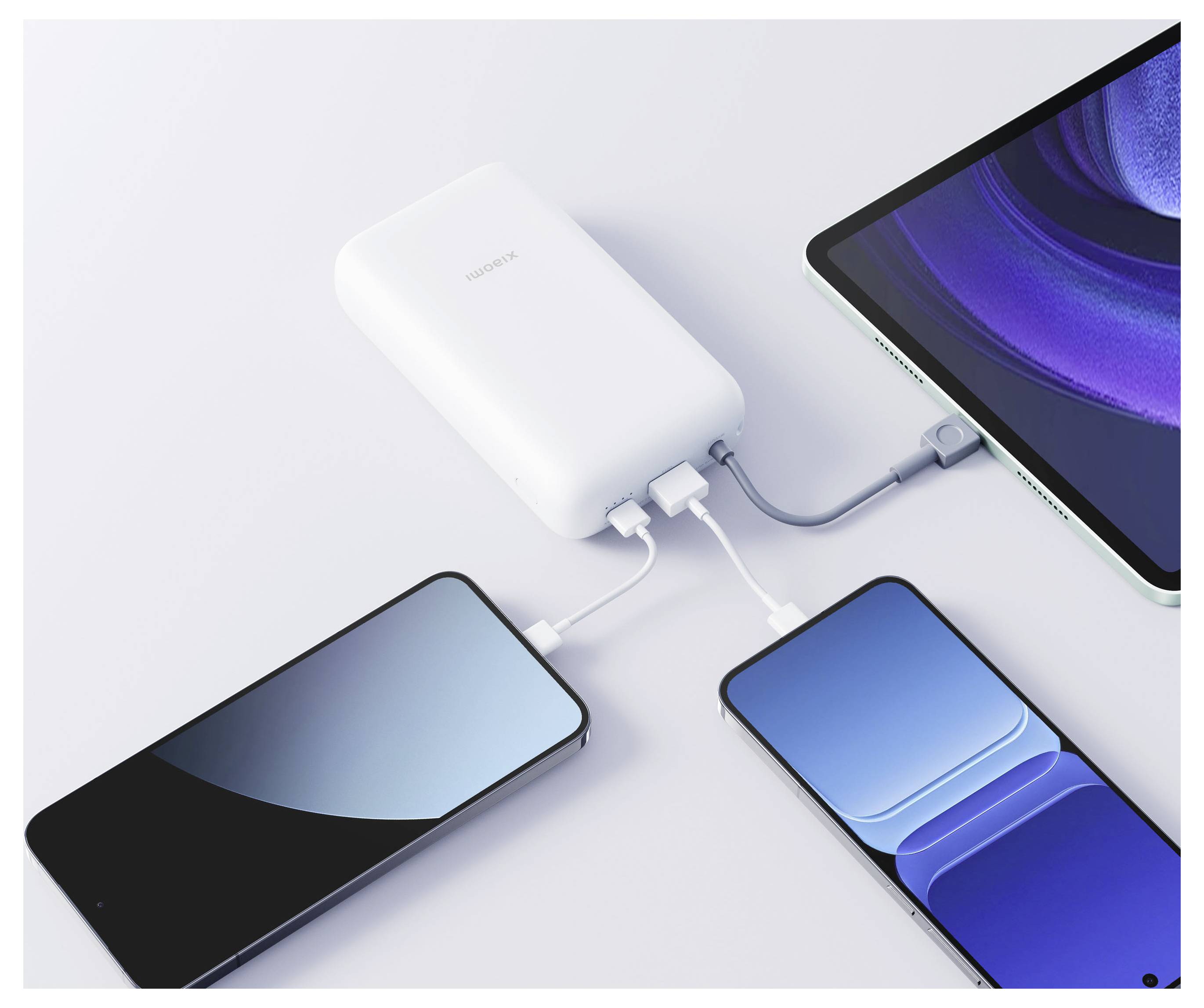 Weiße Huawei-Powerbank lädt drei Geräte auf: ein Telefon, ein Tablet und ein weiteres Telefon, die durch Kabel auf einer hellen Oberfläche verbunden sind.