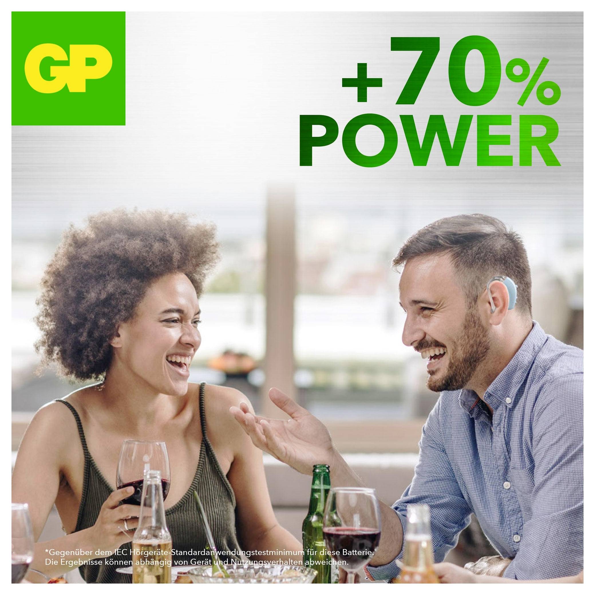 Zwei Personen lächeln und unterhalten sich an einem Tisch, mit GP-Branding und dem Text „+70% LEISTUNG