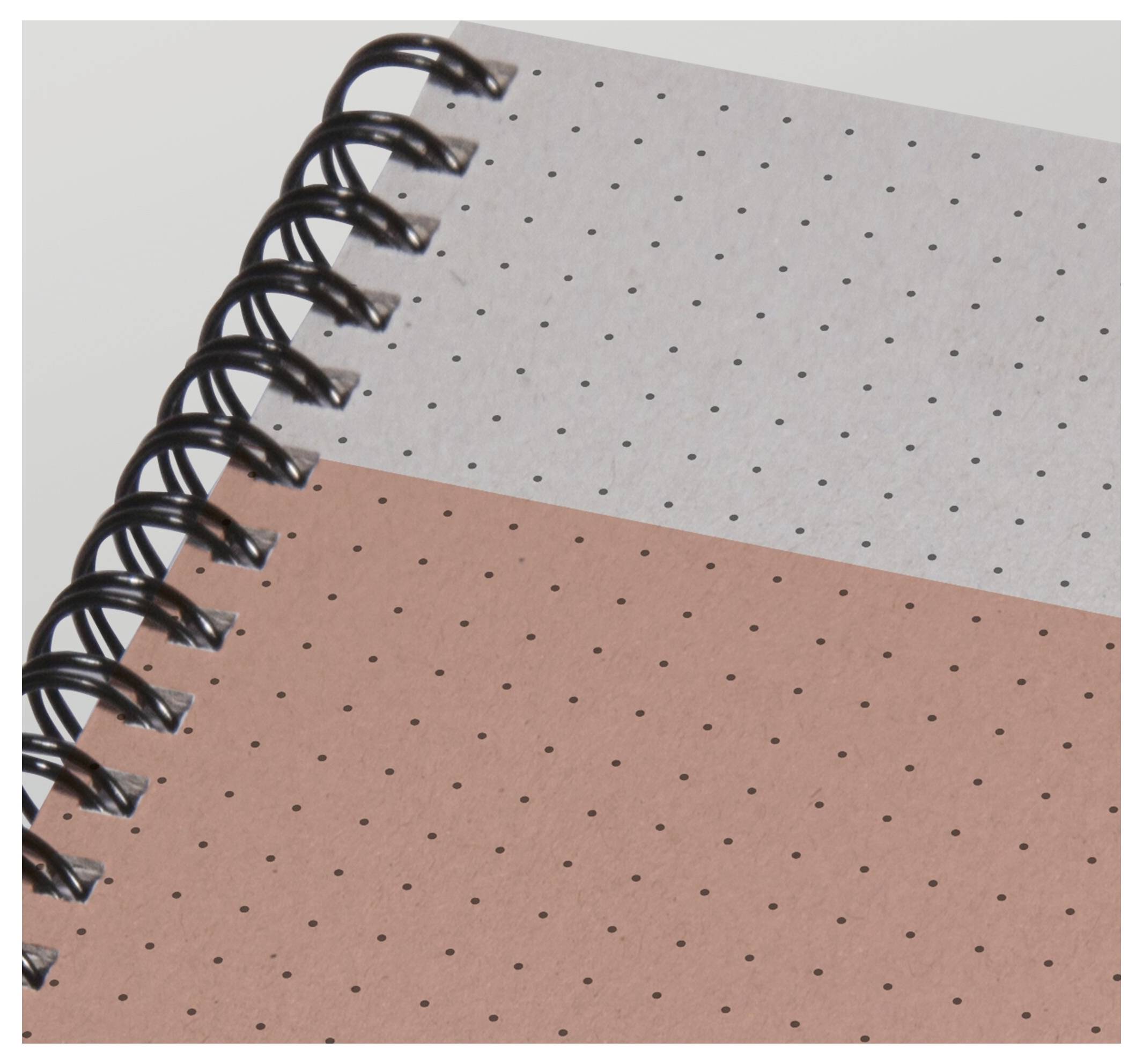 Nahaufnahme eines spiralgebundenen Notizbuches mit Punktmuster und zweifarbigem grauem und rosa Umschlag.