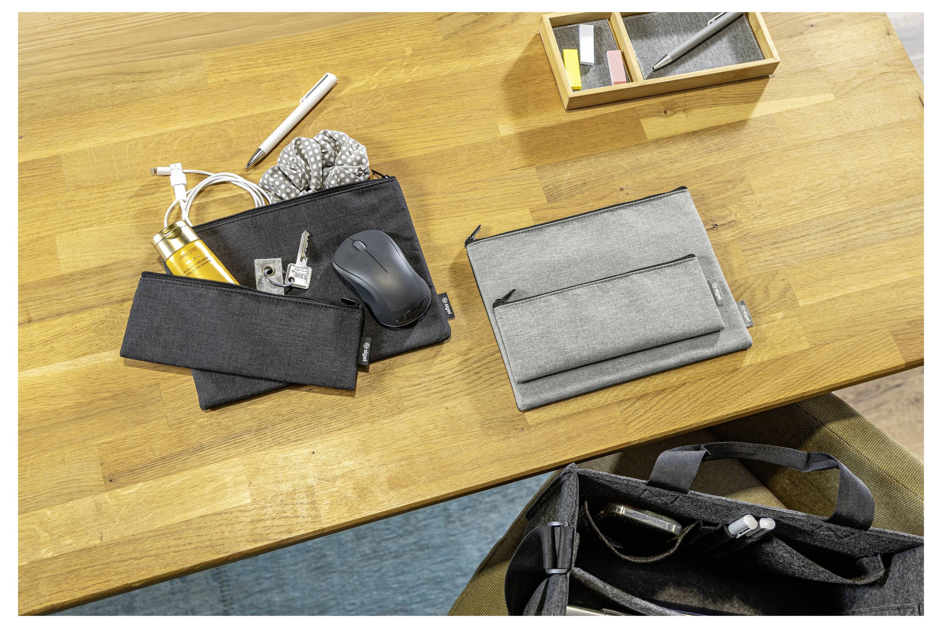 Schreibtisch mit zwei Reißverschluss-Täschchen-Organisern, eines offen mit Kabelzubehör und Maus, das andere geschlossen neben einer Stifteablage und einer Tasche.