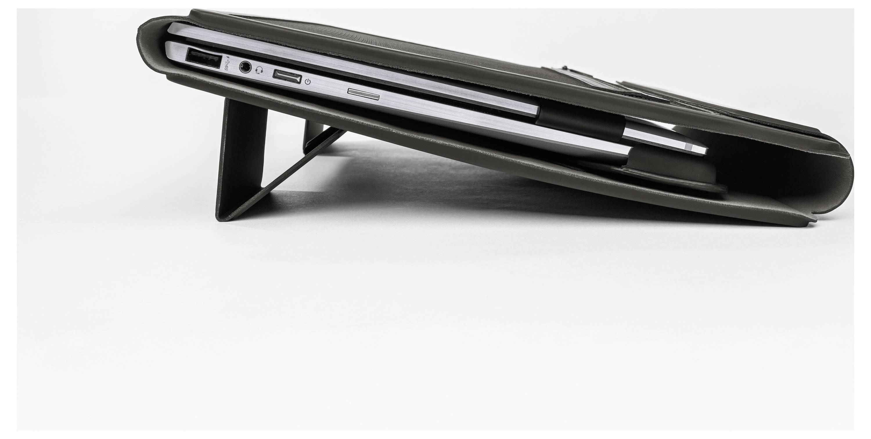 Seitenansicht eines schwarzen Laptops in einem Schutzständer, der seine Anschlüsse und sein schlankes Profil auf weißem Hintergrund zeigt.