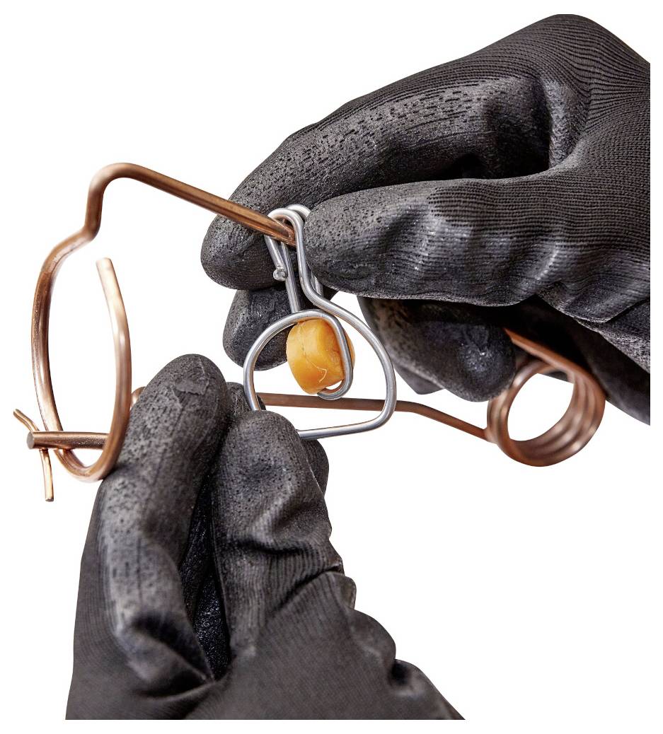 Behandschuhte Hände verwenden ein Metalldraht-Puzzle mit einer orangefarbenen Perle auf weißem Hintergrund.