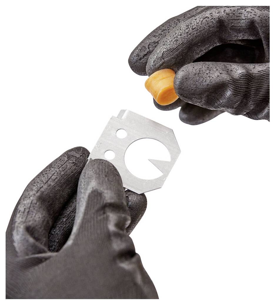 Behandschuhte Hände halten eine kleine Metallschneideklinge und eine orangefarbene Kappe, gezeigt auf weißem Hintergrund.