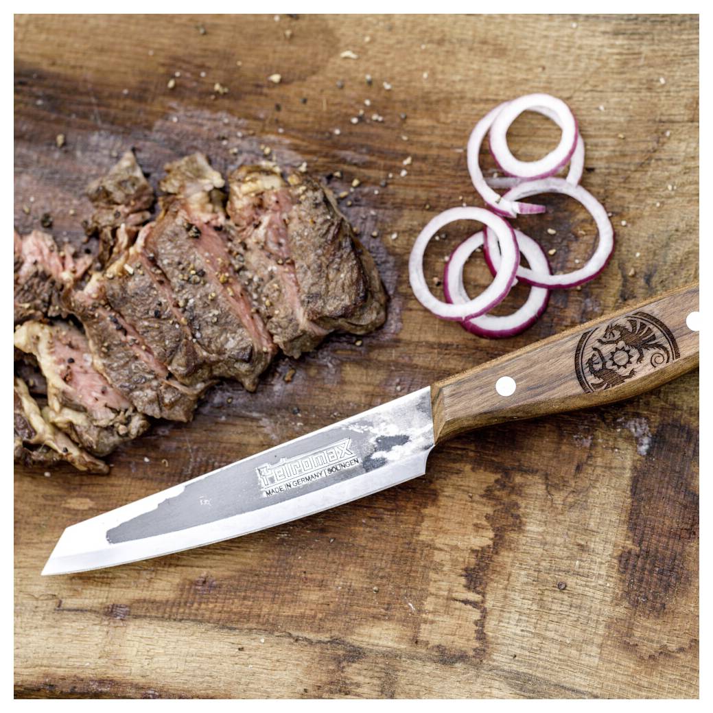 Geschnittenes gegrilltes Steak auf einem Holzschneidebrett mit roten Zwiebelnringen und einem Tranchiermesser mit Holzgriff