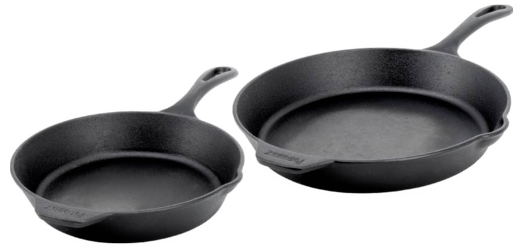Zwei schwarze Gusseisenpfannen, eine kleinere und eine größere, auf weißem Hintergrund dargestellt.