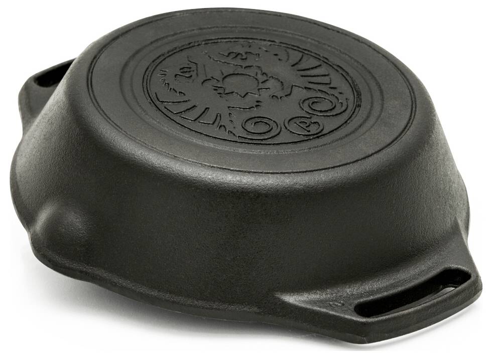 Schwarze Gusseisenpfanne mit dekorativem geprägtem Deckel oder Boden, auf weißem Hintergrund mit Seitengriffen dargestellt.