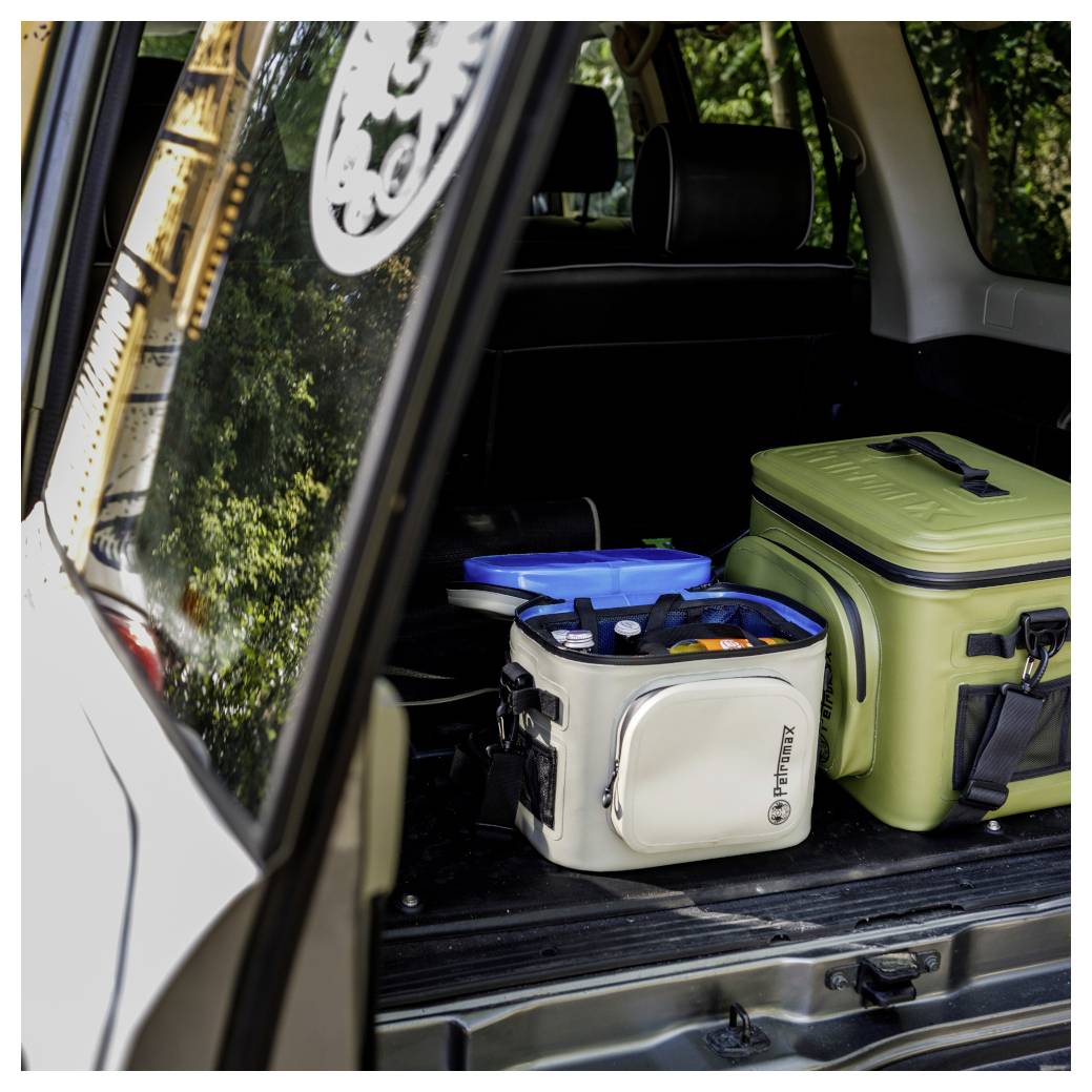 Offener SUV-Ladebereich mit zwei isolierten Kühlertaschen und einem blauen Behälter auf dem Boden, was auf verpackte Lebensmittel oder Getränke für die Reise hindeutet.