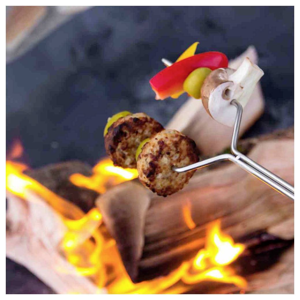 Kebabs mit Gemüse, die über einem offenen Lagerfeuer grillen und auf einem Spieß über den Flammen gehalten werden.