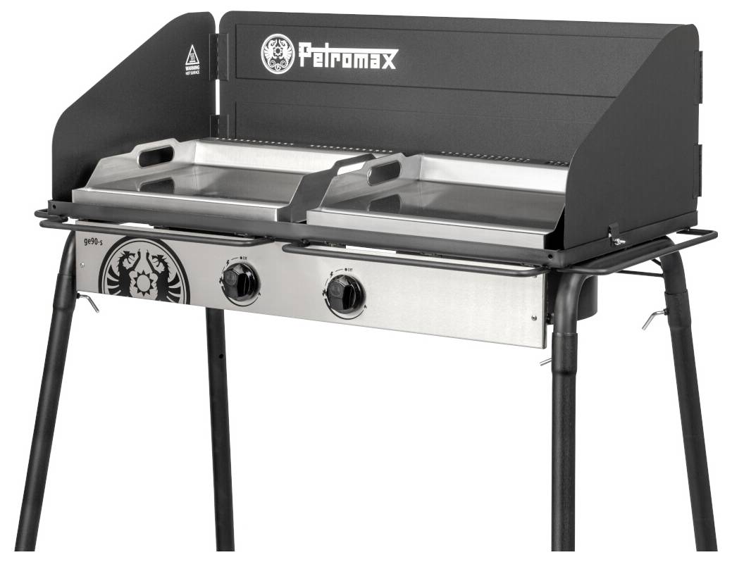 Petromax Tischgrill mit zwei Brennern, Deckel, Edelstahl-Kochfläche, Bedienungsknöpfe an der Vorderseite und Gestell auf vier Beinen.