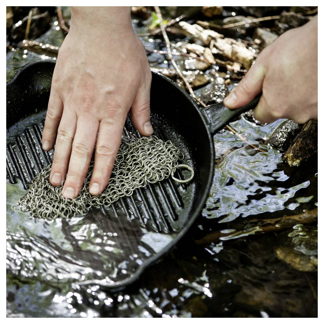 Hände waschen Goldwasch-Material in einer schwarzen Pfanne in flachem Flusswasser.