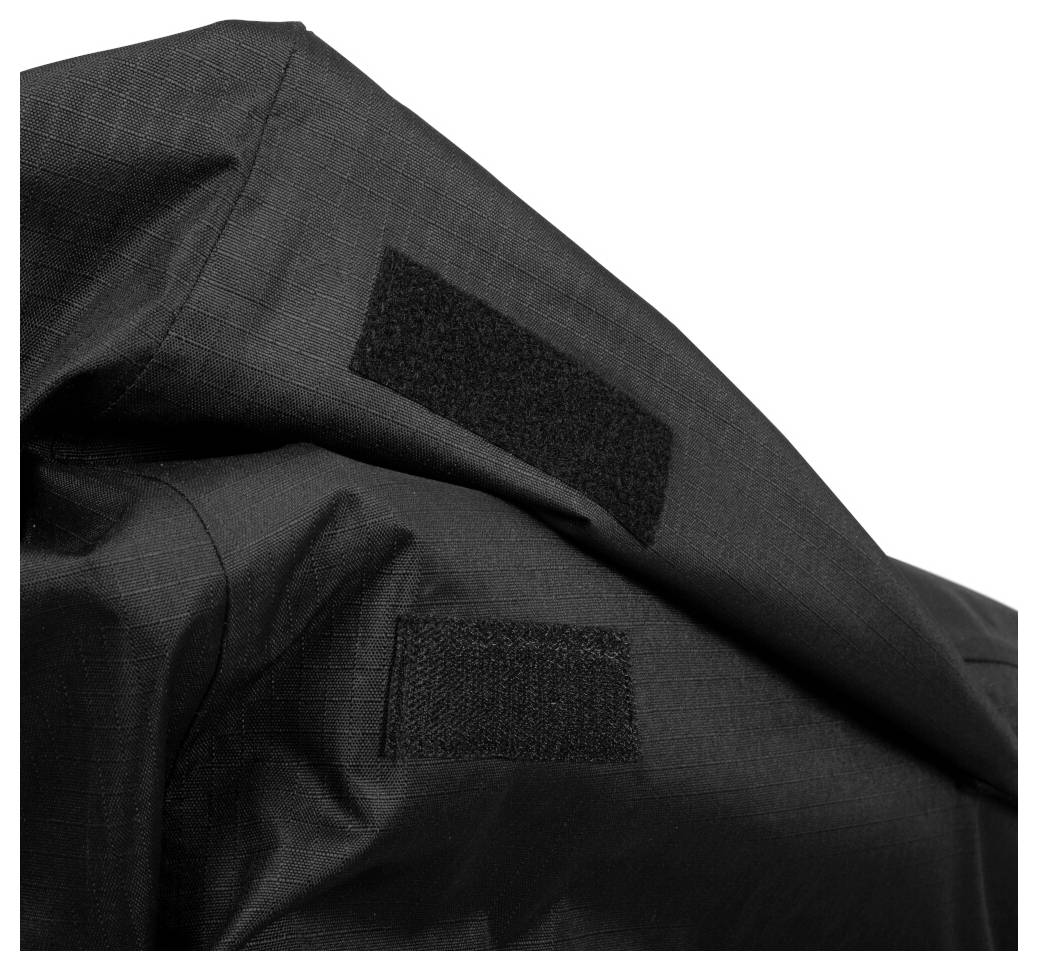 Nahaufnahme von schwarzem Stoff mit zwei aufgenähten Klettverschluss-Flecken auf einem strukturierten Kleidungsstück oder einer Tasche.
