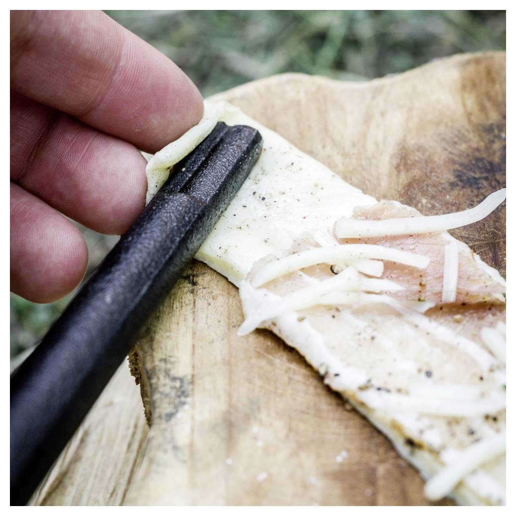 Hand benutzt Stäbchen, um einen Fischstreifen von einem Holzbrett zu heben, belegt mit einer dünnen weißen Garnierung.