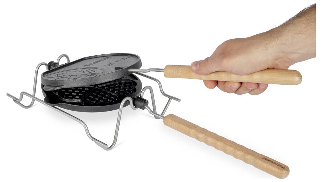 Hand, die eine Waffeleisen über einem Metallständer hält, als würde sie das runde Gitter öffnen oder schließen.