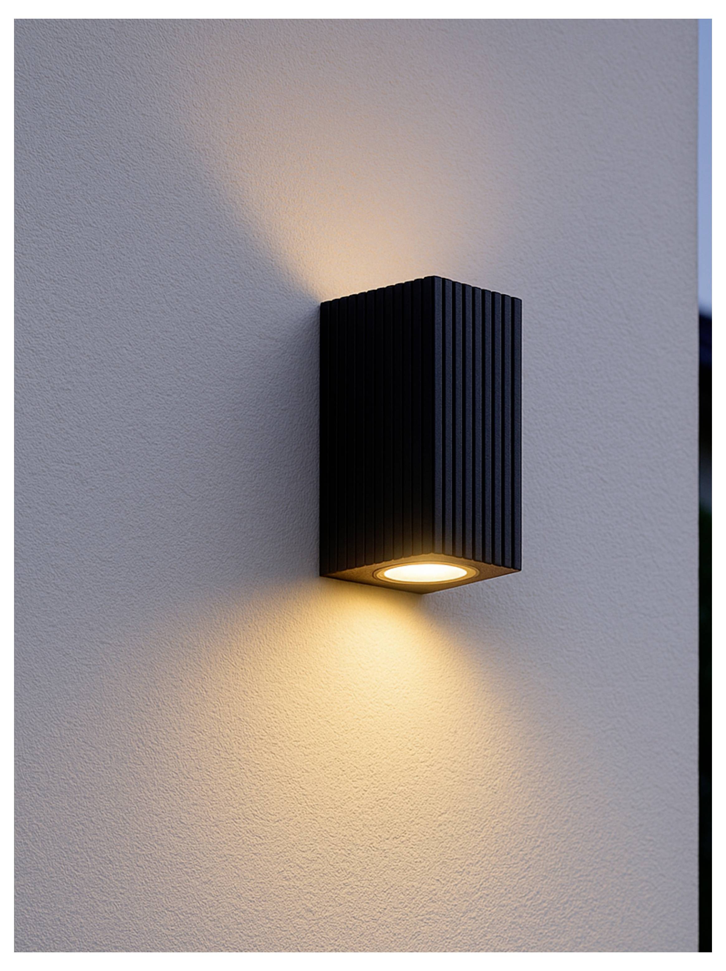 Schwarze Wandleuchte an einer hellgrauen Wand, die warmes Licht nach oben und unten wirft.