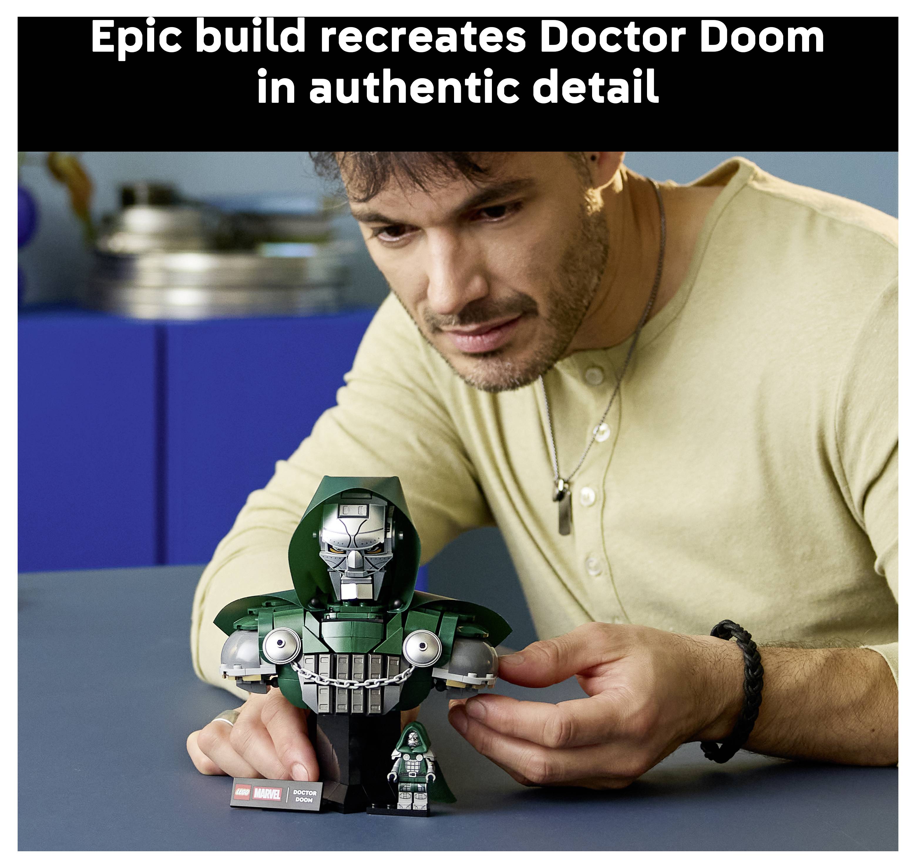 Ein Mann zeigt einen detaillierten LEGO Doctor Doom Bausatz und eine Minifigur, während der Text oben sagt „Epischer Bausatz recreates Doctor Doom in authentischer Detailtreue