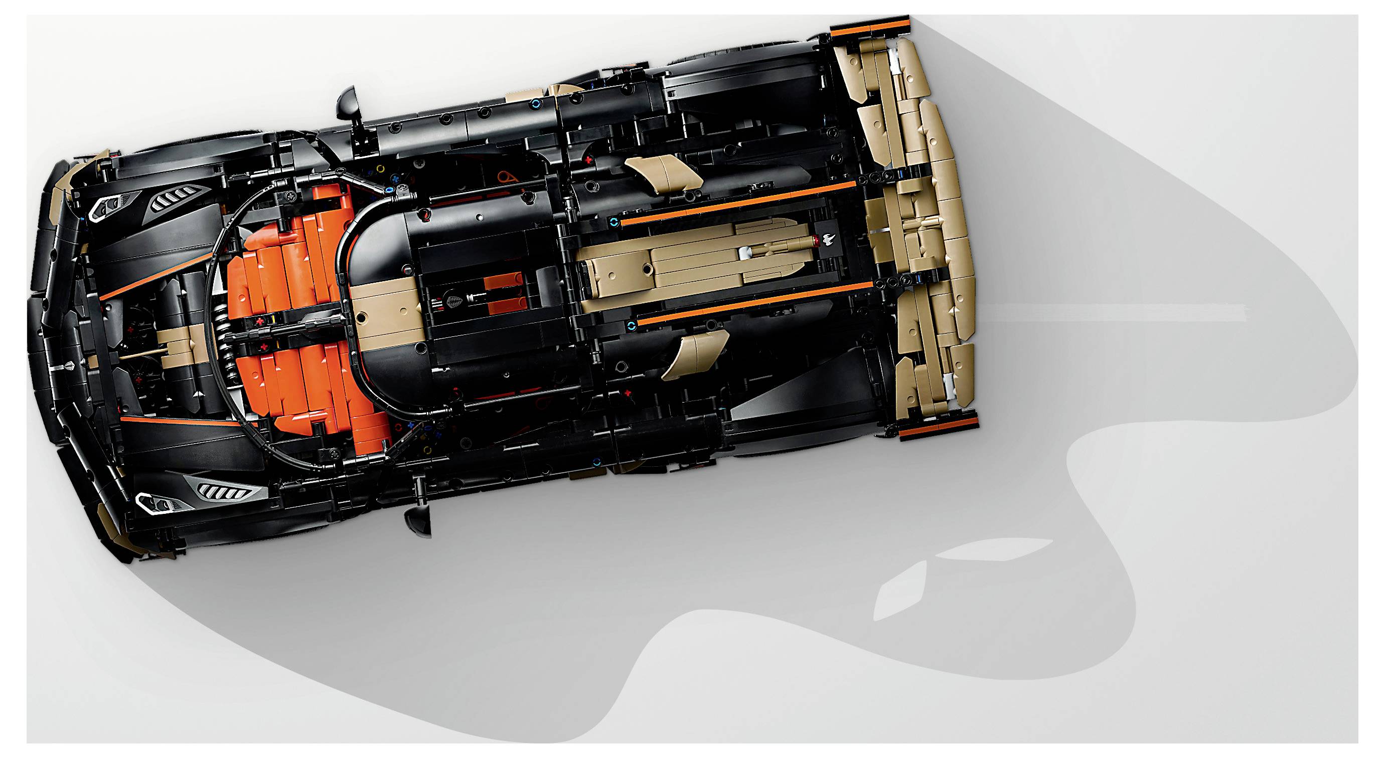 Draufsicht eines schwarz-orange Automobil-Chassis/einer Baugruppe auf hellem Hintergrund, die die innere Struktur und Komponenten des Fahrzeugs zeigt.
