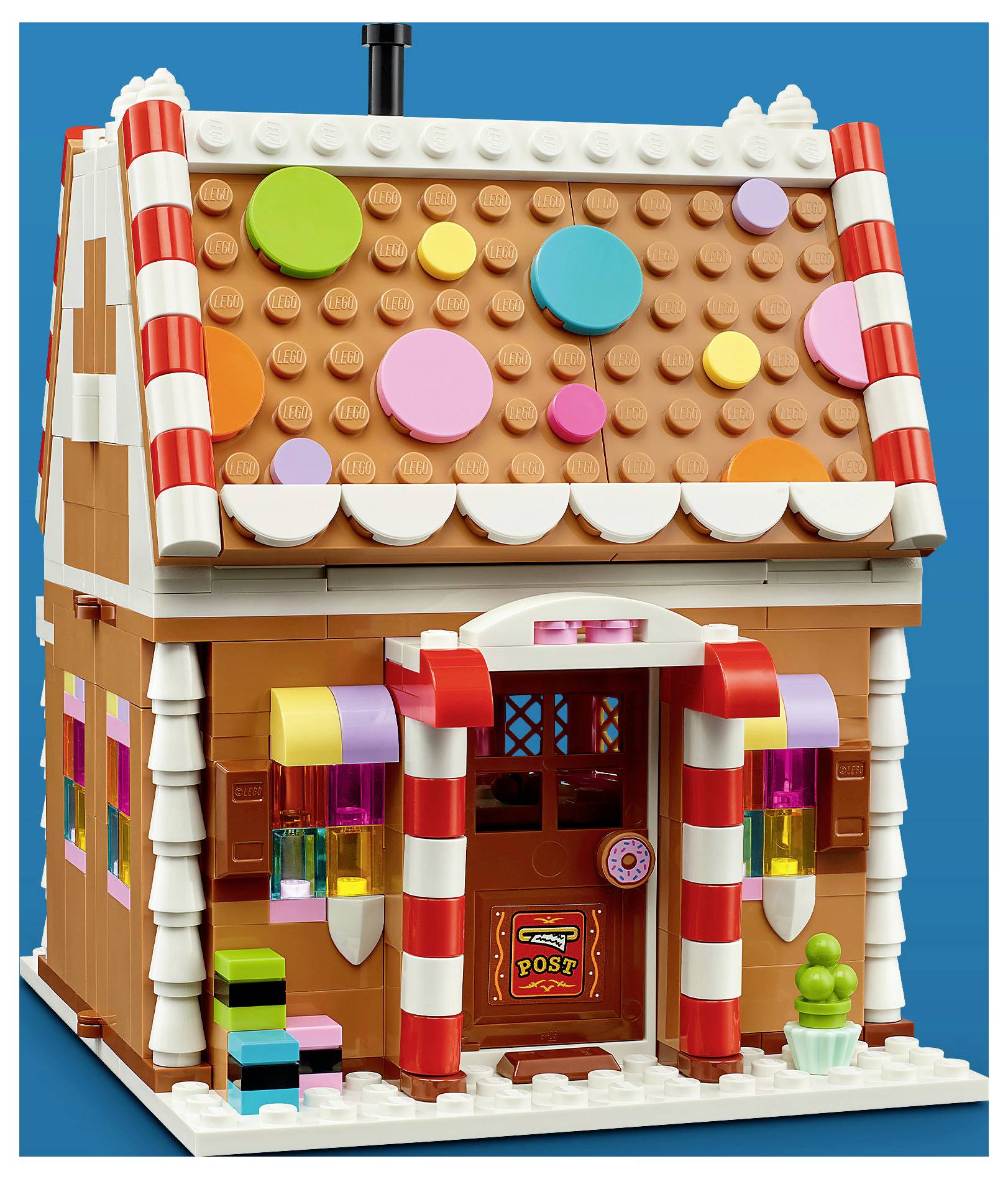 Ein farbenfrohes LEGO-Lebkuchenhaus im Stil mit Süßigkeitsdekoration, gestreiften Säulen, einer Eingangstür mit der Aufschrift „POST