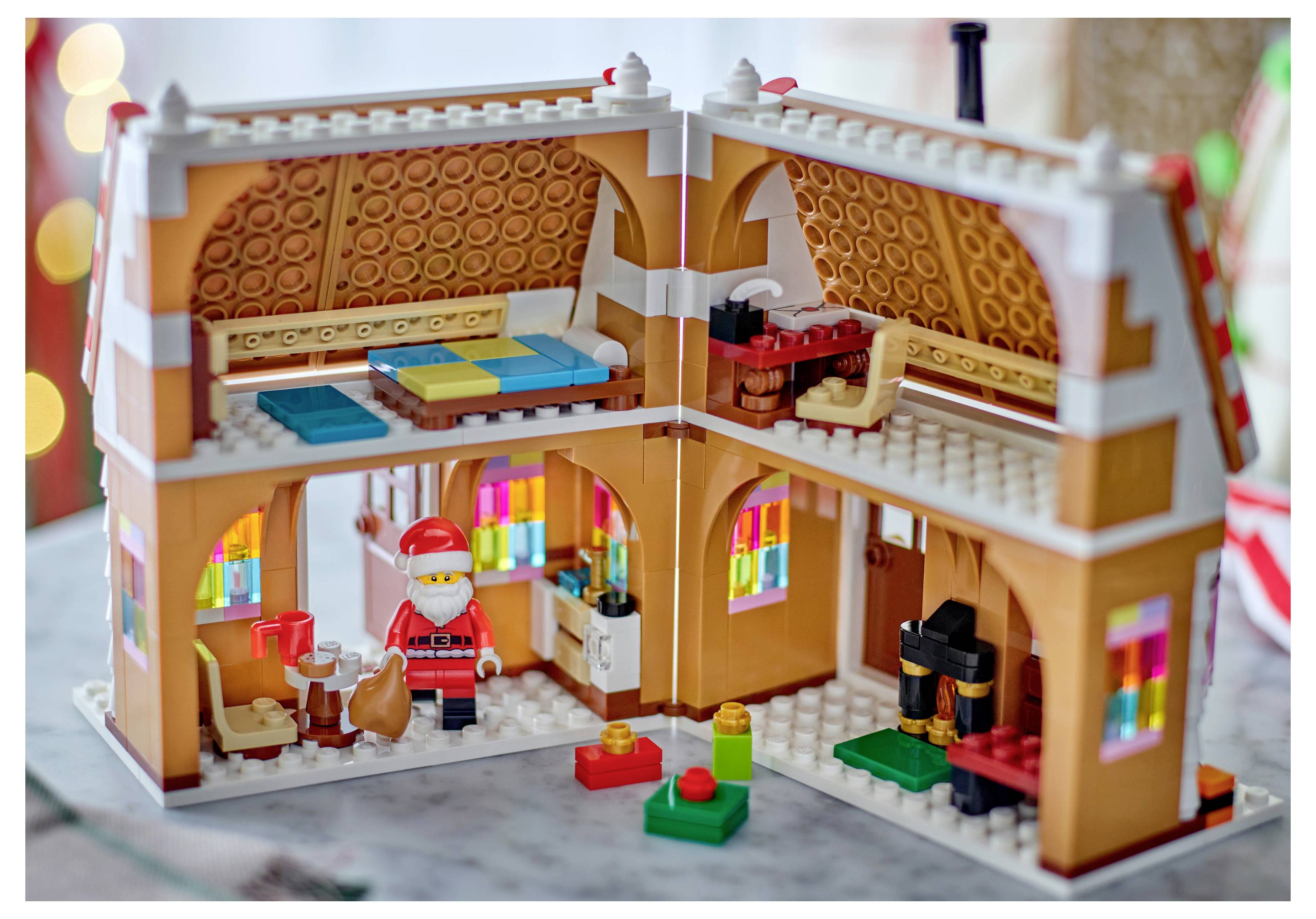 Offene LEGO-ähnliche Hausausschnittdarstellung mit dem Weihnachtsmann im unteren Raum, einem Bett und Regalen im Obergeschoss und kleinen festlichen Accessoires im Inneren.