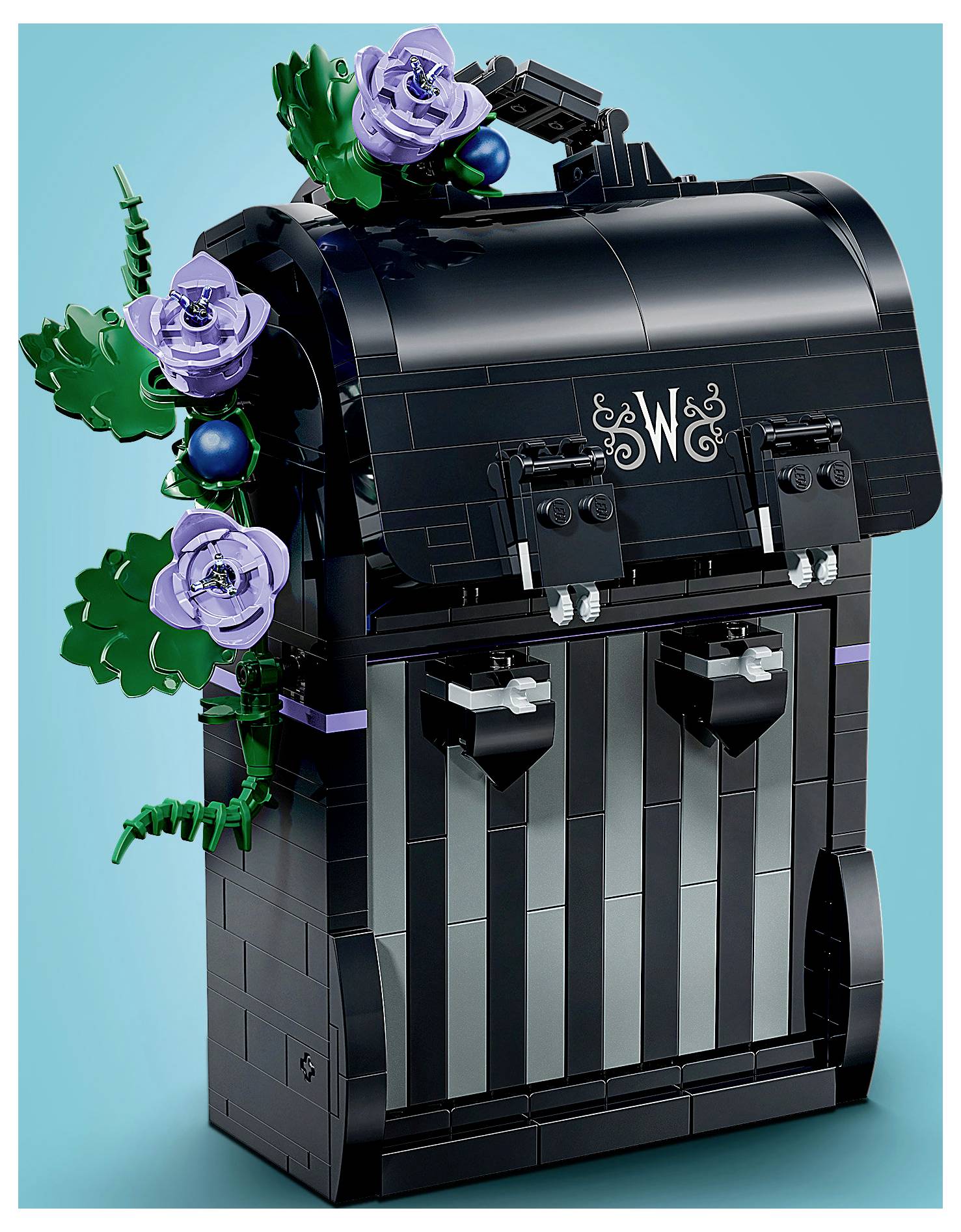 Schwarze LEGO-ähnliche Truhe oder Schrank mit Lavendelblüten und grünen Ranken auf türkisfarbenem Hintergrund, mit einem "W&"-Monogramm auf der Vorderseite.